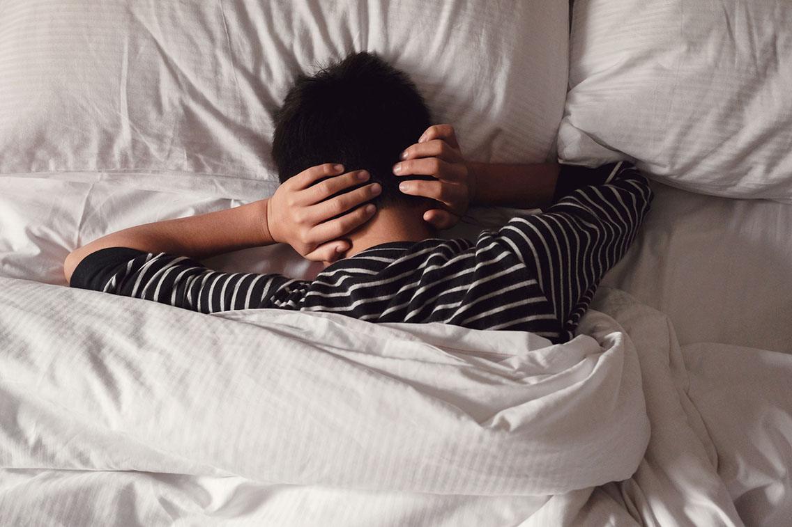 Preteen tween boy covering ears with his hands in bed, ADHD, Autism,sleep disorder, mental health in children, not want to hear, wake up kid for school concept