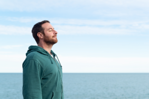 man with anxiety who is now calm and standing at the ocean