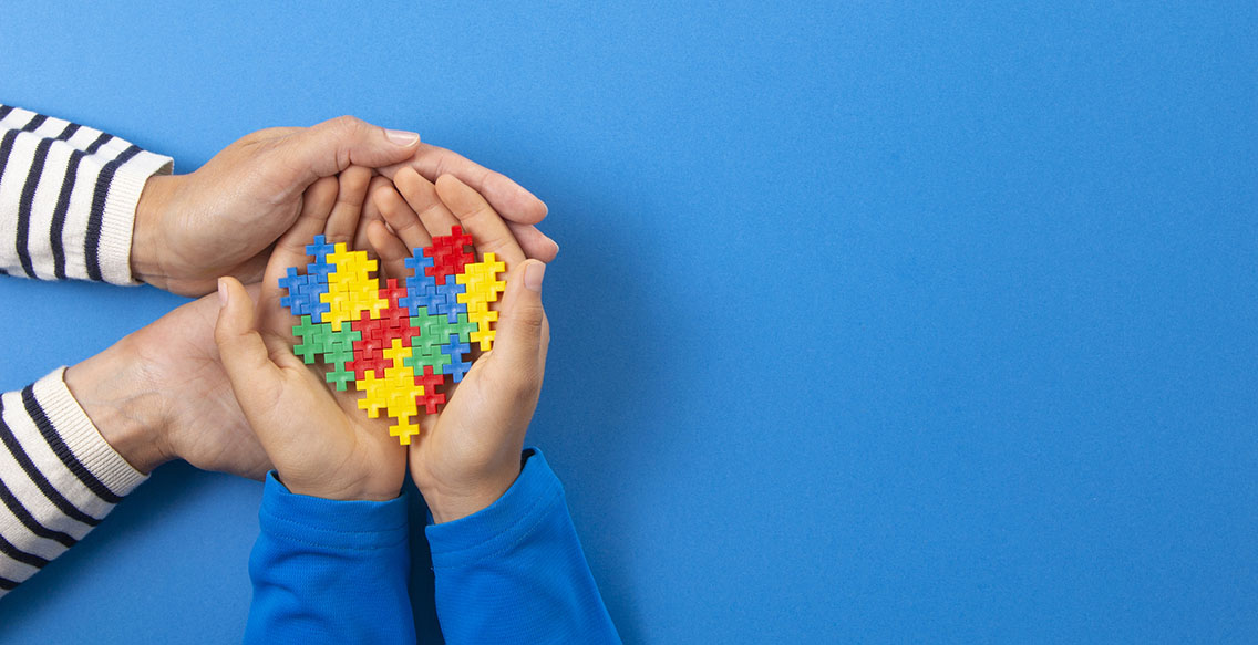 Autism awareness concept. Mother and Child hands with heart symbol made of puzzle pieces