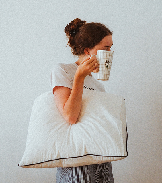 tired woman with a cup of coffee and a pillow