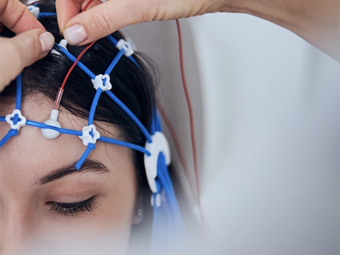 Closeup of a woman getting a qEEG with electrodes being placed on her head