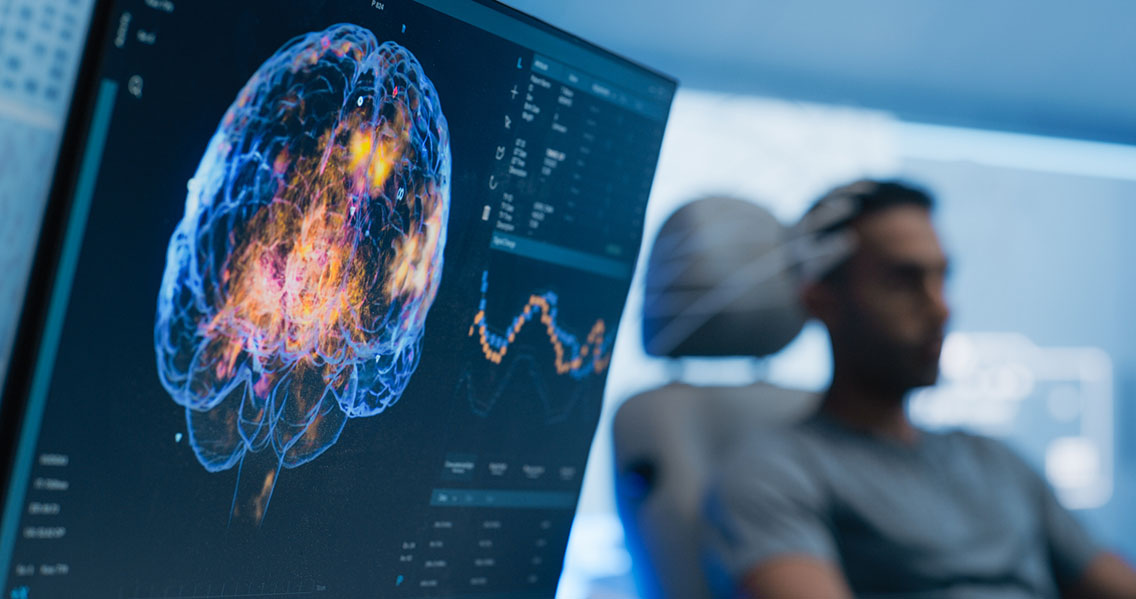 Man getting a qEEG scan, with the computer readout in front and the man in the background